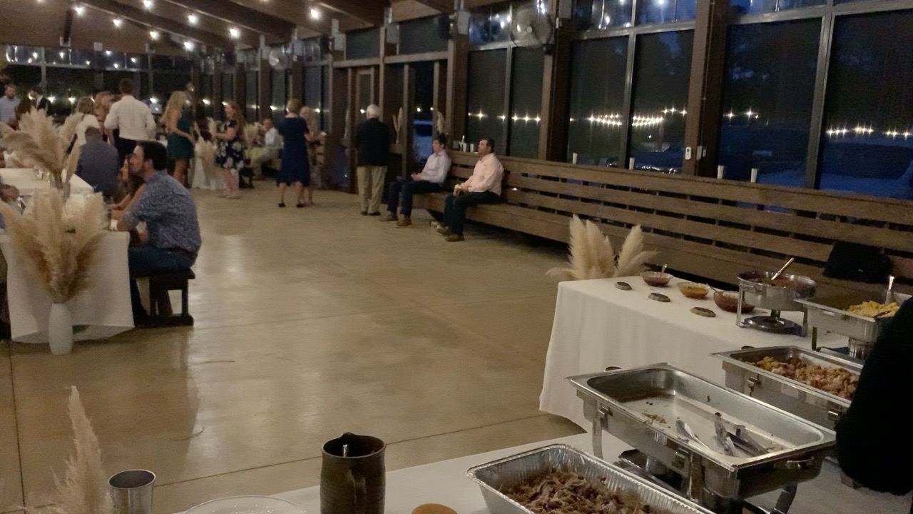 Guests mingling inside the pavilion near buffet tables at night